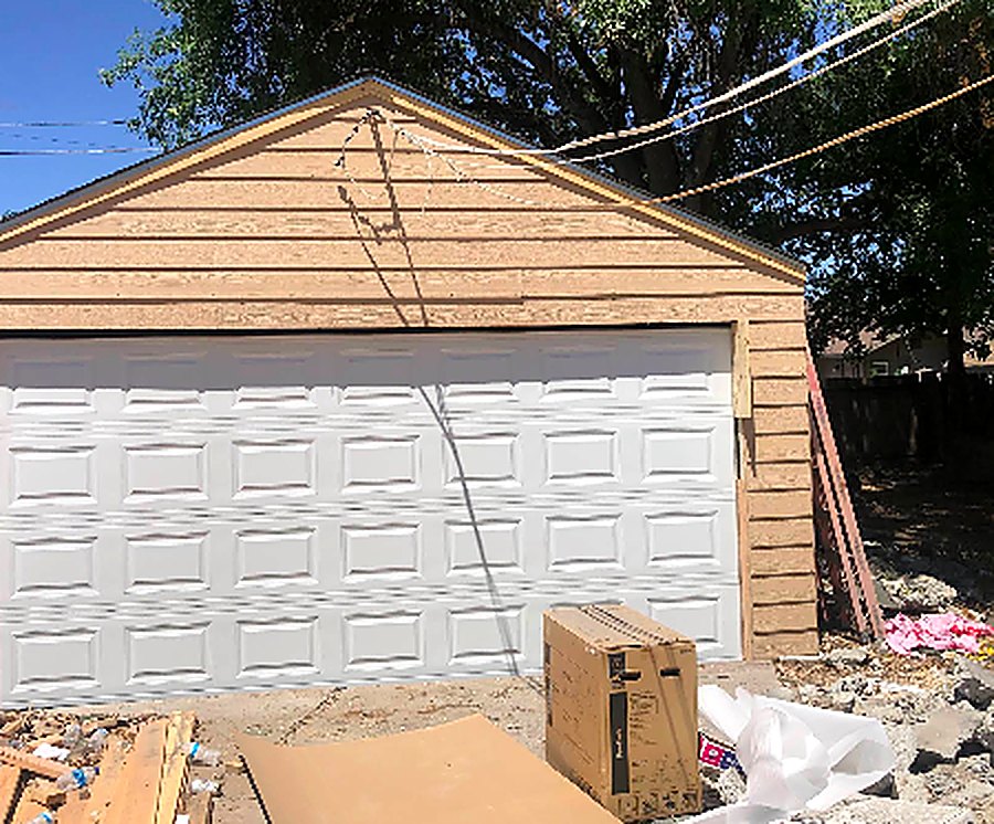 New white raised-panel garage door installed on a detached garage in Manteca