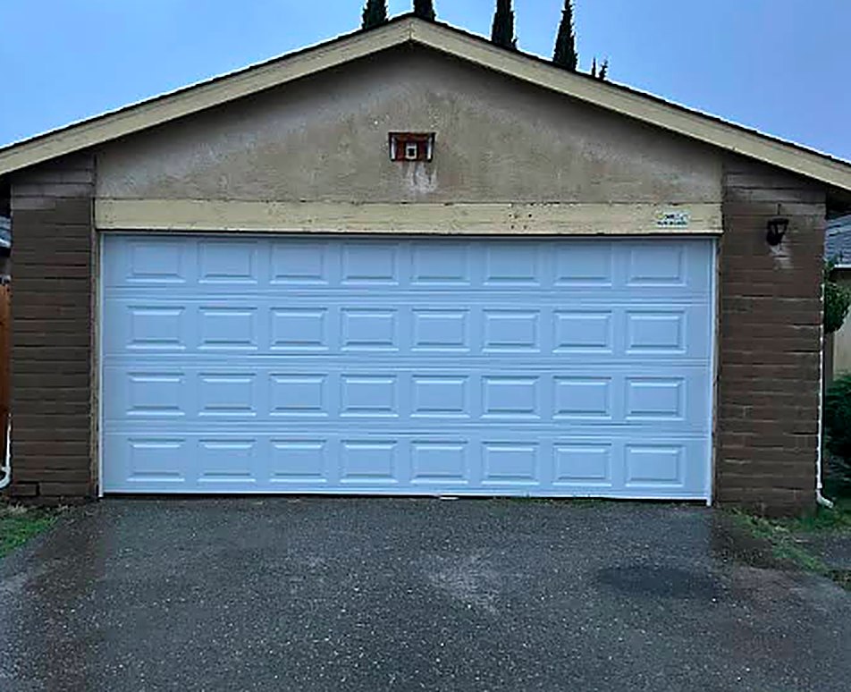 White raised-panel garage door replacement on a brick garage in Stockton